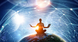 person sitter på jordkloden med universet i bakgrunnen og en laptop i hånden